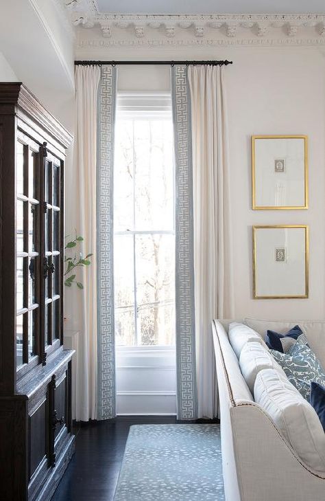 White curtains with a blue Greek key trim hang in front of a window from an oil rubbed bronze curtain rod and beside stacked gold framed art. Blue Window Treatments, French Pleat Curtains, Classic Curtains, Living Room Classic, White Couch, Design Window, Transitional Living, Blue Curtains, Trendy Living Rooms