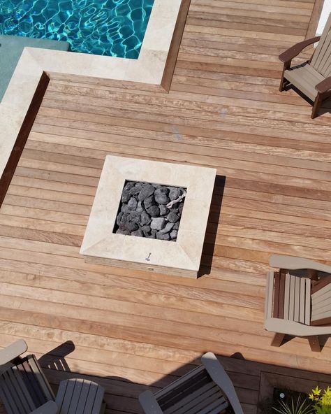 Travertine creates clean lines and a high-end look for this square fire pit on a pool deck made of ipe wood. Volcanic rock fills the natural gas fire pit, which has a stainless steel burner. The modern fire pit and pool area is designed by Atlanta-based Hearthstone Environments. Ipe Pool Deck, Wood Pool Deck, Travertine Pool Decking, Wood Decking, Deck Fire Pit, Travertine Pool, Natural Gas Fire Pit, Modern Fire Pit, Pool Remodel