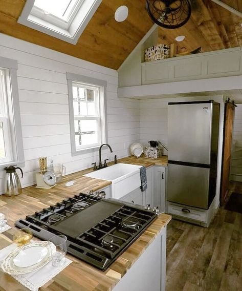 The tiny house kitchen features custom cabinetry with toe-kick drawers, a butcher block countertop, white farmhouse sink, full size gas range, and refrigerator with bottom freezer. Tiny House Kitchen Storage, Rustic Tiny House, White Farmhouse Sink, Trendy House, Tiny House Luxury, Cozy Loft, Tiny House Listings, Tiny House Kitchen, Tiny Spaces