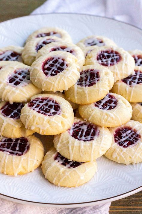 Raspberry Thumbprint Cookies are a fun treat to make with the kids! Buttery cookies with fruity filling and vanilla glaze are dessert lovers dream! #BreadBoozeBacon #cookies #raspberry #holidays Fruity Christmas Cookies, Cookies Raspberry, Raspberry Butter, Raspberry Thumbprint, Raspberry Dessert, Raspberry Thumbprint Cookies, Bread Booze Bacon, Chocolate Thumbprint Cookies, Cookie Recipe Video