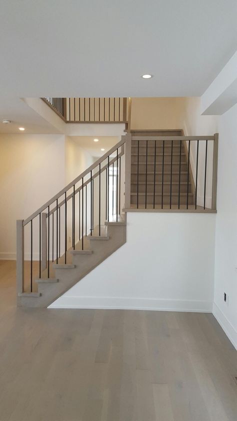 White Oak stair constructed with closed risers, closed stringer both sides Railing system constructed with 2'' square handrail, 3'' square plain posts and 1/2'' square black metal spindles  Stained and finished to clients selected colour Black Metal Spindles, Metal Spindles Staircase, Metal Spindles, Stairs Stringer, Handrail Design, House Staircase, Flooring For Stairs, Oak Stairs, Stair Railing Design