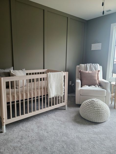 Baby nursery rocker crib room accent wall green paint cozy Nursery With Dark Green Accent Wall, Green And Dark Wood Nursery, Greens For Nursery, Sage Green And Brown Nursery, Gender Neutral Green Nursery, Nursery Green Accent Wall, Baby Nursery Accent Wall, Nursery Green Walls, Green Accent Wall Nursery