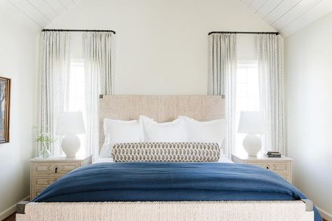 Bedroom features an abaca headboard with blue bedding and a tan and blue bolster pillow flanked by cream nighstands lit by Aerin Toulon white egg lamps. White Egg, Transitional Bedroom, Bolster Pillow, Blue Bedding, Lamps, Egg, Pillows, Bedroom, Cream