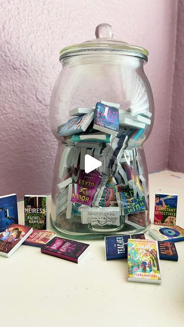 Katie Reads Fiction on Instagram: "✨ Introducing my new TBR Jar! ✨  I have wanted to make a TBR jar for the longest time, but I could never decide on how I wanted it to look. I thought about mini scrolls or mini pills in a vending machine, cute folded notes in jar, and everything in between. It finally clicked when I saw what @bookbowlchallenge created! I loved hers and wanted to create my own take on the mini books. I made something similar with my mini book ornament a couple years ago, so I followed the same instructions but tweaked the design and size. When I’m done, the books will sit on their own mini bookshelf!  First up is The Tainted Cup by Robert Jackson Bennett! I just love seeing the mini next to the real book!  Do you have a TBR jar? . . . #thetaintedcup #robertjacksonbennett # Tbr Jar, Bookish Crafts, Log Ideas, Mini Bookshelf, Book Ornament, Folded Notes, Reading Logs, Reading Log, Program Ideas