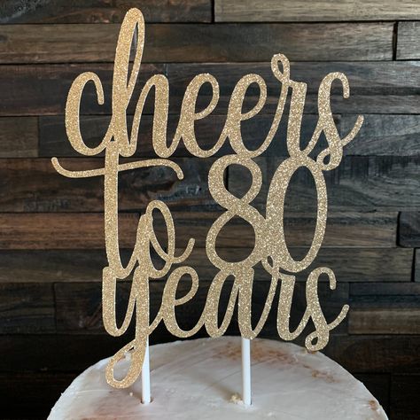 "This listing is for a \"cheers to 80 years\" glitter cake topper (white on backside). Topper measures 5 1/2\" wide x 7\" tall and is attached to 2, 6\" white lollipop sticks. This topper will add the perfect touch to your 80th celebration! Please select a color from the drop-down menu. Custom colors available upon request. See the link below for coordinating banner. https://www.etsy.com/listing/755870903/cheers-to-80-years-banner-cheers-to-80?ref=shop_home_active_165&frs=1 *Please leave a note 70th Birthday Party Ideas For Mom, 80th Birthday Cake Topper, Cheers To 80 Years, 60th Birthday Cake Toppers, Round Birthday Cakes, 80th Birthday Cake, 80th Birthday Party Decorations, 80th Birthday Decorations, 80 Birthday Cake