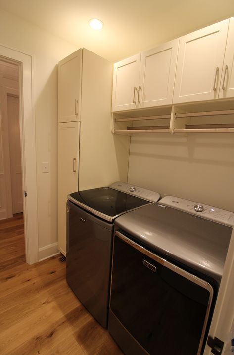 Laundry Room Hanging Bar Between Cabinets, Laundry Room Tall Storage Cabinet, Laundry Room With Under Cabinet Basket, Pantry Cabinet Laundry Room, Small Laundry Room Built In Cabinets, Tall Cabinet In Laundry Room, Hanging Mops And Brooms Laundry Rooms, Cleaning Closet In Laundry Room, Multipurpose Laundry Room Ideas