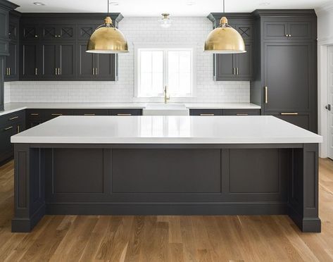 Black Kitchen Cabinets with White Quartz Countertop, White Oak Hardwood Floor, Brass accents and white subway tile with dark grout. Dark inset cabinets bring a modern feel to this classic kitchen. The overall size of the kitchen is 21’6” wide by 13’6” deep. The kitchen island is roughly 11’ wide by 4’6” deep. Kitchen lighting is Eugene Large Pendant - Hand-Rubbed Antique Brass from Circa Lighting. Black Kitchen Cabinets with White Quartz Countertop, White Oak Hardwood Floor, Brass accents and wh Floors With Black Cabinets, Black Kitchen Floors, Black Paint Kitchen, White Tiled Kitchen, Paint Kitchen Island, Dark Hardwood Floors, Dark Grout, Kitchen Cabinet Trends, Dark Hardwood