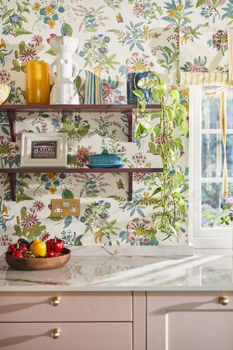 Open shelving on floral wallpaper. Shelves display pictures, vases and plants with a bowl of colourful fruit and veg on the white worktop. Casa Casuarina, Sophie Robinson, Pearl Wallpaper, Woodland Floral, Maximalist Interior, Harlequin Wallpaper, Wallpaper Trends, Wallpaper Direct, Country Garden