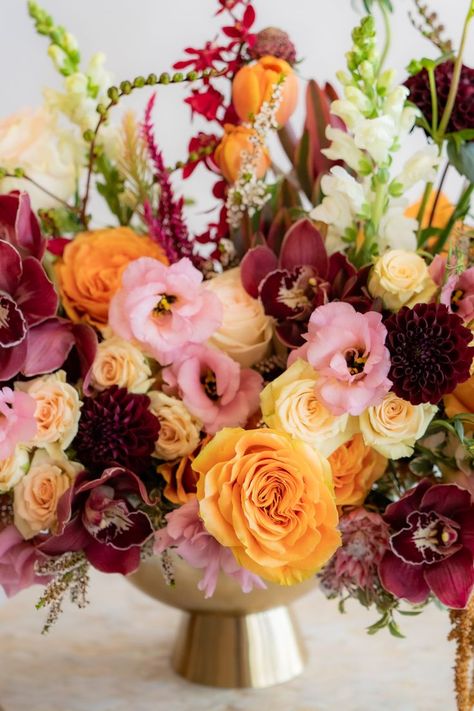 maroon, orange, and pink flower arrangement in gold container Coral And Burgundy, Centerpieces Wedding Orange, Red Pink Yellow Flower Arrangement, Pink Orange Burgundy Flowers, Burgundy Pink Yellow Wedding, Maroon Pink Orange Wedding, Red And Yellow Floral Arrangements, Maroon Flower Arrangements, Orange And Maroon Wedding