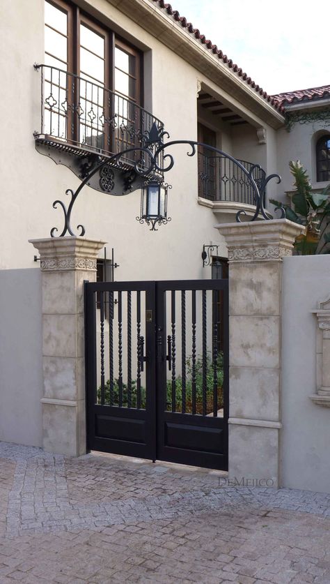 A classic and custom wrought iron entry gate, complimented by an accent arch, is an eye catching feature added to this Spanish style home. Iron Side Gate Ideas, Spanish Wrought Iron Gates, Front Door Iron Gate, Spanish Style Fence, Classic Gate Design, Outdoor Gate Design, Small Gate Design, Gate Door Design, Iron Gates Design