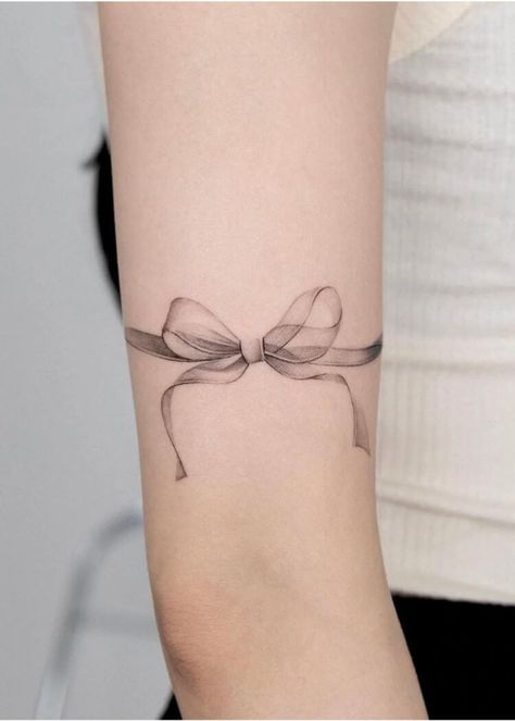 Explore bow tattoo meaning. Discover the symbolic meaning behind bow tattoos and get inspired with our collection of unique bow tattoo designs and bow tattoo ideas. Ribbon Arm Tattoo, Ribbon Bracelet Tattoo, Ribbon With Flowers Tattoo, Simple Ribbon Tattoo, Thigh Ribbon Tattoo, Vintage Bow Tattoo, Bow Bracelet Tattoo, Knee Bow Tattoo, Bow Tattoo Lower Back