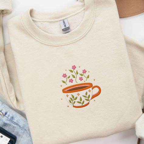 𝑪𝒖𝒑 𝒐𝒇 𝑻𝒆𝒂 𝒆𝒎𝒃𝒓𝒐𝒊𝒅𝒆𝒓𝒆𝒅 𝒔𝒘𝒆𝒂𝒕𝒔𝒉𝒊𝒓𝒕 ☕️🌸 Wake up and smell the style with our Cup of Tea/Coffee Embroidered Sweatshirt! ☕️ Indulge in your caffeine cravings with our meticulously embroidered floral coffee design. Whether you’re wearing cute matching sweaters with your friends, going outside for a walk or shopping, staying cozy at home with family, or simply adding to your crewneck collection, this unisex sweatshirt is perfect for you! Our crewnecks are made from the highest quality fabric for a... Hem Embroidery, Cozy At Home, Matching Sweaters, Cute Matching, Coffee Design, Embroidered Sweatshirt, Coffee Lover Gifts, Embroidered Sweatshirts, Cup Of Tea