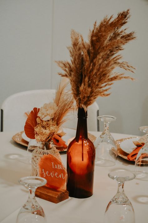 Amber Flower Vases Wedding, Autumn Boho Wedding Decorations, Minimalist Fall Wedding Centerpieces, Amber Jar Centerpiece, Fall Floral Arrangements Wedding Centerpieces, Burnt Orange Wedding Centrepiece, Wedding Reception Table Set Up, Burnt Orange Centerpieces Wedding, Amber Vases Wedding Centerpieces