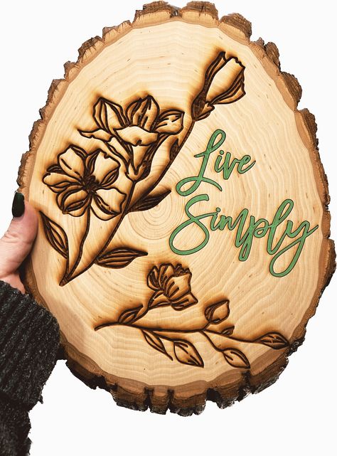 "The Live Simply design is laser engraved on a circular piece of barked edge basswood. This one is a kind sign is painted with acrylic and sealed. Add a touch of nature to your home or office with this special piece of art! Perfect for a house warming present, holiday present, birthday present, or more.    Size:  Approximately 11\" x 4\" Oval size. And .5\" deep.  Medium: Acrylic and laser wood engraved on a barked basswood plank.  It is finished with a clear spray varnish.  Hanging Options - A gator tooth hanger is provided but not fixed.  Please hang the sign in a sheltered area out of direct sunlight and rain to keep the sign looking new.  Additional Info: The wood has light sanding, but the may not be entirely smooth.  This one-of-a-kind sign is ready for shipping. I offer FREE standar Wildflower Art, Art Live, Wood Slice Art, Wood Burning Crafts, Live Edge Wood, Live Simply, Engraved Wood, Wood Slices, Live Edge