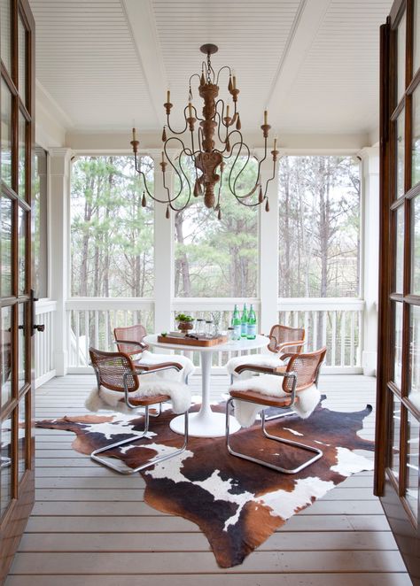 Relaxing screened-in porch with wooden deck, cowhide, modern chairs and double doors | Homedit Ikea Sheepskin Rug, Eclectic Porch, Screened Room, Screened Deck, Balcony Modern, Victorian School, Traditional Porch, Inspiring Outdoor Spaces, Porch Chairs