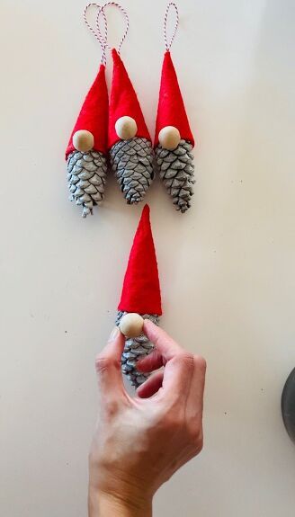 Make these adorable christmas gnomes in minutes using pine cones. If you like these cute gnomes, let me show you how to make them. Step 1 collecting pine conesI selected a variety of pine cones, I tried to pick up the big ones. Step 2 painting the pine conesI used white spray paint to color my pine cones and left them dry. Step 3 making the hat I used red felt fabric for the hat. I cut a small piece of felt that is like a quarter of a circle. Step 4 the hat I gave the felt… Gnomes From Pinecones, Pine Cone Gnomes Diy, Pinecone Gnomes Diy, Pinecone Christmas Crafts, Pine Cone Gnomes, Pinecone Gnomes, Diy Christmas Gnomes, Gnome Christmas Ornaments, Clothes Pin Ornaments