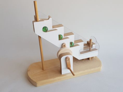 Wooden Stair Marble Machine plans and patterns. You will find a step by step guide pattern to create your own marble machine by using wooden materials. This wooden marble machine consist of a mobile stair that moves the marbles from bottom to the top of the toy. By turning the hand crank the mobile stairs take the marbles to the top and then they drop to the bottom by using the gravity. And the cycle goes on as a loop. #marblemachine #woodenplans #woodworking #woodentoy Marble Toys, Marble Clock, Marble Machine, Diy Playground, Mechanical Clock, Marble Run, Wooden Staircases, Machine Pattern, Wooden Stairs