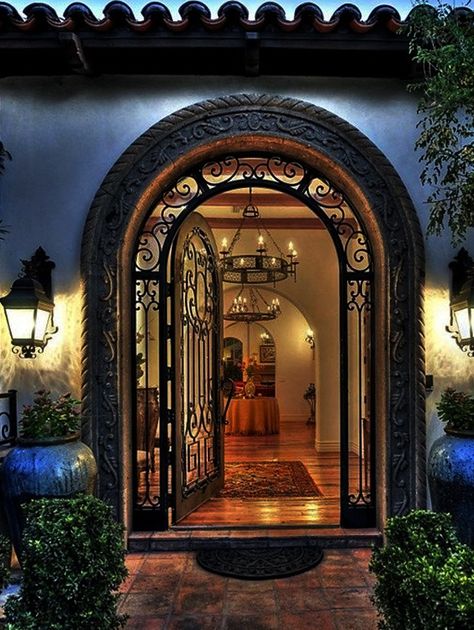 This metal door with the round top and molded cement trim is a modern spin on the old style homes of Spain.  The metal is hand worked to create the intricate patterns that provide security as will as beauty and style.  #luxurydoor #doordesign Mediterranean Entrance, Exterior House Doors, Garden Escape, Rustic Front Door, Mediterranean Mansion, Main Entrance Door Design, Main Entrance Door, Front Gate Design, Entrance Gates Design