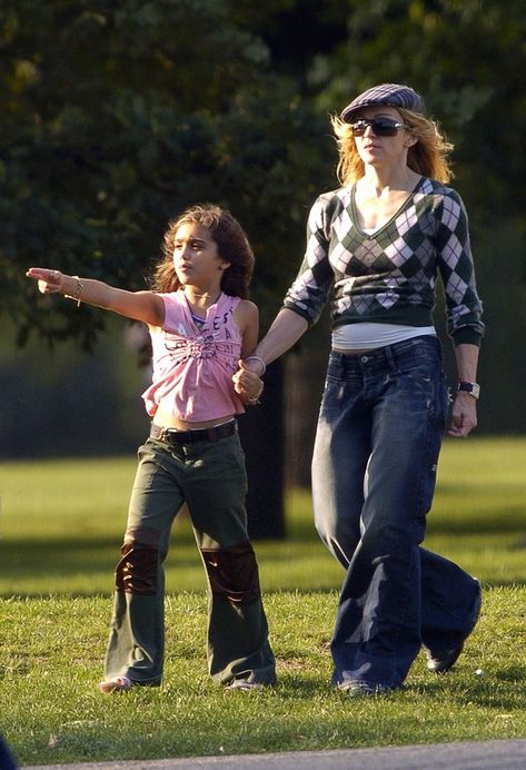 In 2004, Madonna and Lourdes wore coordinating flared jeans to the park. Madonna Kids, Madonna Family, Black Silk Midi Dress, Dark Grey Coat, Ripped Tights, Cher Photos, Lady Madonna, Denim Capri Pants, Studded Leather Jacket