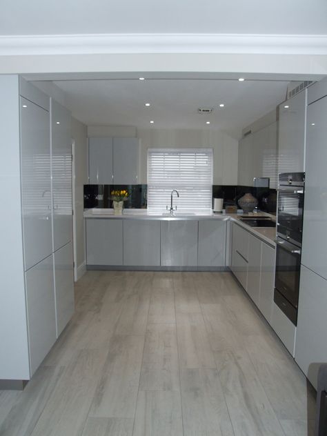 A beautifully bright and modern handleless kitchen in high gloss light grey with designer white Corian worktops. This seamless look is paired with the latest Siemens appliances and a contemporary grey mirrored glass splashback. #Bright #Modern #Whitekitchen #LightGreyKitchen #Corian #DesignerWhite #Siemens #MirroredGlassSplashback #ColliersKitchens #Contemporary #Seamless Worktop Ideas, Grey Kitchen Interior, Grey Gloss Kitchen, Light Grey Kitchen, Gloss Kitchen Cabinets, Light Grey Kitchen Cabinets, Modern Grey Kitchen, White Gloss Kitchen, Grey Kitchen Floor