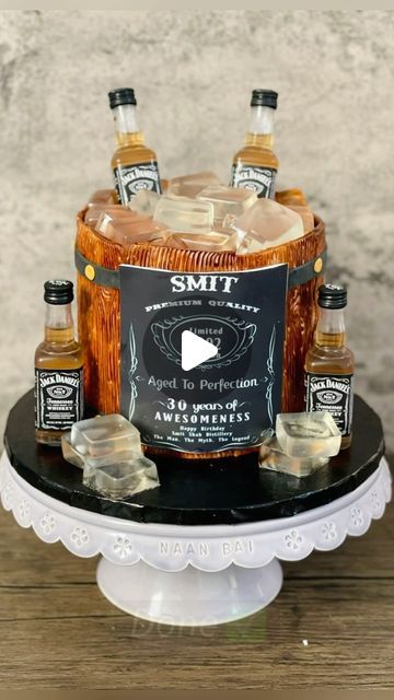 Ankita Dutta | CAKE ARTIST on Instagram: "Whiskey Barrel Cake!! 🥃 (made this one in Feb 2022 😊) With this whiskey barrel cake, many elements come together to create a very effective design. I’m quite pleased with it! 🥃🎂 It’s the little details that make a difference, such as the jelly ice cubes, the wood-textured fondant, and the fondant hoops and rivets. (The ice cubes can be made with gelatin or with agar agar, for a vegetarian option.) You can use a spray if you have access to one. Wait for the paint to dry before applying other fondant decorations. The label is edible too ☺️ Flavor - eggless chocolate with eggless chocolate buttercream (The song is so apt for this reel 🥴) #barrelcake #whiskeycake #birthdaycakeideas #fondantcake #fondantcakes #cakeformen #cakeideas #cakereels #c Edible Ice Cubes For Cakes, Whiskey Barrel Cake Ideas, Barrel Cake Design, Whiskey Cake Design, Whiskey Barrel Cake, Fake Ice Cubes, Barrel Cake, Whiskey Cake, Beer Barrel