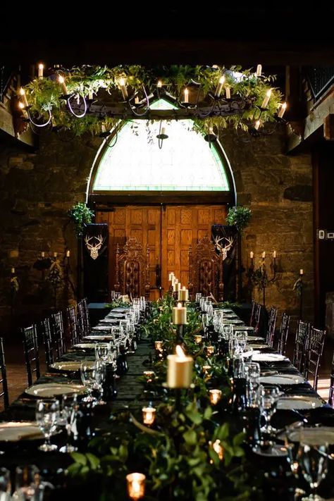 Picture of a LOTR wedding reception space indoors, with a black table with greenery and gold candles, a greenery chandelier with vines Elven Wedding Reception, Viking Wedding Table Centerpieces, Celtic Woodland Wedding, Game Of Thrones Wedding Aesthetic, Medieval Centerpieces Wedding, Enchanted Wedding Table Decor, Fantasy Centerpieces Wedding, Midevil Wedding Theme Ideas, Fantasy Wedding Ceremony