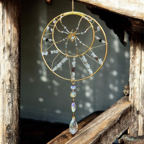 This stunning gold and garnet suncatcher is adorned with a dazzling glass spider and quartz crystals, bringing whimsy and wonder to your space! The delicate hand-made design features quartz and garnet crystals wrapped around a gold hoop with a delicate glass-beaded spider in the middle. Larger glass prisms dangle below to catch the light and create a mesmerizing display of rainbows.    Hang this one of a kind sparkly spider design in a sunny window to enjoy its shimmering beauty all day, or enjoy it as a unique and eye-catching accent in any space. The sun will shine through all of the stones and glass prisms. Handcrafted with care and attention to detail, this quartz crystal spider sun catcher is a genuine work of art that will bring joy and inspiration to your home for years to come! Det Spider Suncatcher, Copper Suncatcher, Window Sun Catchers, Hanging Crystals Diy, Crystal Spider, Beaded Suncatcher, Copper Wire Crafts, Glass Spider, Spider Design