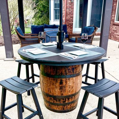 Complete the outdoor oasis of your home or business with our new outdoor whiskey barrel pub tables. Handcrafted from recycled poly-lumber, these tabletops are weather resistant, moisture resistant, and maintenance free! The tabletops sit affixed to a fully refurbished and restored authentic whiskey barrel. The barrels have been cleaned, sanded, stained, and finished with an exterior and marine grade polyurethane for superior protection. | Loon Peak® Finnlaidh Dining Table Wood / Plastic in Black Outdoor Pub Table, Whiskey Barrel Table, Wine Barrel Table, Whiskey Barrel Furniture, Patio Table Set, Solid Oak Table, Pub Tables, Oak Table Top, Barrel Table