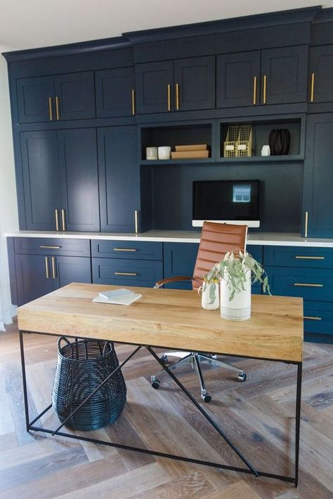 a stylish home office with a navy storage unit, a catchy industrial desk of wood and metal, a leather chair and a wicker basket Blue Gold Office, Blue Home Offices, Office Styling, Navy Cabinets, Office Blue, Modern Desk Chair, Office Built Ins, Cabinets Painted, Home Office Cabinets