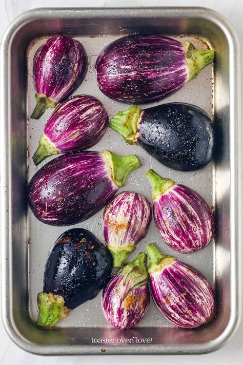 Oiled and seasoned mini eggplants on a small baking sheet. How To Roast Eggplant In Oven, Baby Eggplant Recipes Simple, Fairy Tail Eggplant Recipes, Small Eggplant Recipes Easy, Purple Eggplant Recipes, Graffiti Eggplant Recipes, Fairytale Eggplant Recipes, Eggplant Appetizer Recipes, Eggplant Recipes Easy Baked