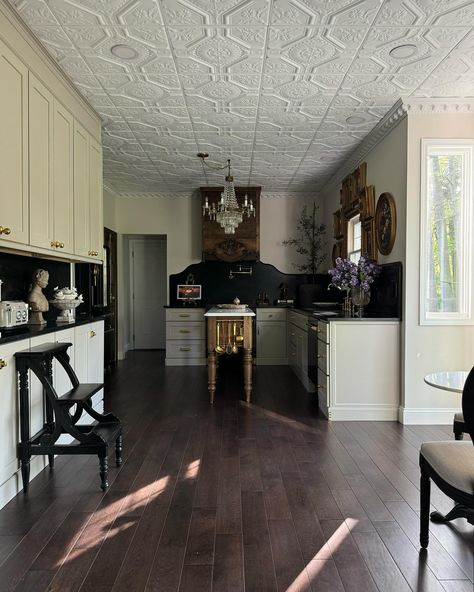 Our Modern Victorian kitchen stills📸 I hope y’all can appreciate the details in the space…the @americantinceilings tiles, the Nero Mist granite counters and tall backsplash with an ogee edge from @graniteworksstone , the antique Italian chandelier, the gorgeous custom dairy table island made by @clevelandcarpentry , the antique floral oil paintings I’ve been collecting , the 1800’s bed frame turned hood vent , the glass bifold pantry with brass @signaturehw Cremone bolts—it all came together ... Bifold Pantry, Dairy Table, Modern Victorian Kitchen, Kitchen Victorian, Table Island, Ogee Edge, Hood Vent, Shaker Style Cabinets, Rta Cabinets