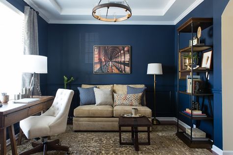 We transformed the formal dining into a masculine navy blue library and office area. We chose navy blue as the color for this masculine home office. We anchored the space with a traditional rug, rich gold accents, wood tones and this masculine leather strapped ottoman. We found a cream armless sofa that was the perfect scale for the room. #mancaveideas #mancavedecor #masculineoffice #homelibrary #masculinelivingroom #masculinedecor #manlyoffice #dwellbycheryl #armlesssofa #manofficedecorhome Home Office Sofa Layout, Home Office Setup With Couch, Navy Cream Gold Bedroom, Navy Blue Home Office Ideas, Office With A Couch Ideas, Masculine Office Guest Room Combo, Home Office Navy Blue, Office And Lounge Combo, Masculine Blue Living Room