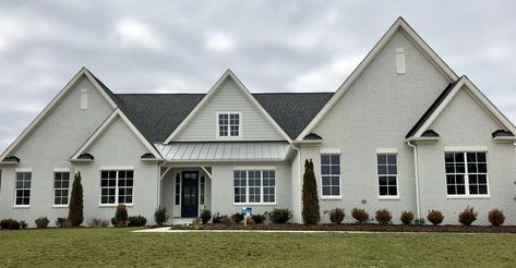 Silverpointe painted brick; Alabaster trim; Glae Force front door; Colonial Slate shingles; white windows; Silver metal roof Silver Metal Roof, Gray Exterior House Colors, Alabaster Trim, Exterior House Paint Color Schemes, Sherwin Williams Exterior Paint Colors, Slate Shingles, Grey Exterior House Colors, Exterior Gray Paint, Colors For 2024