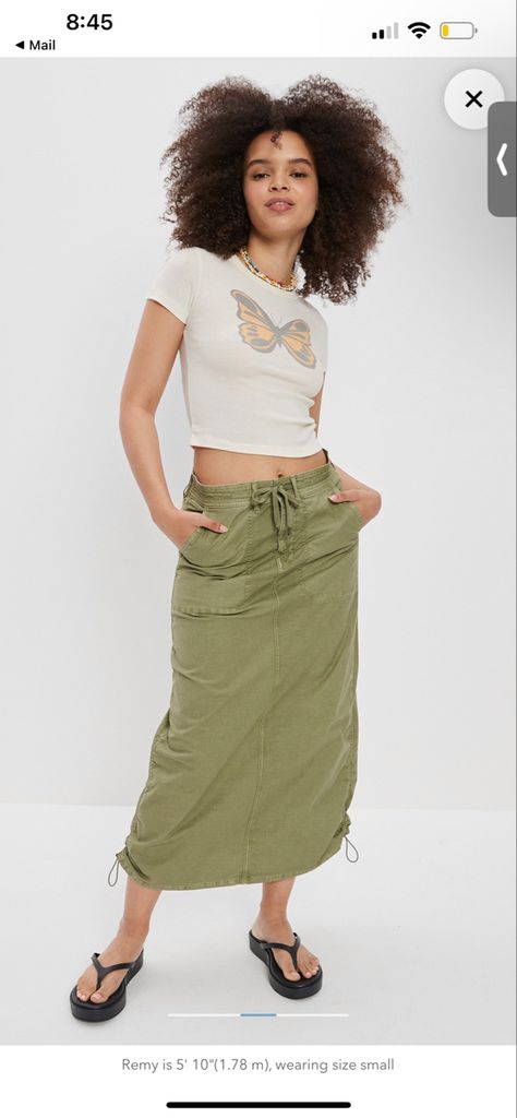 A model wearing a white cropped shirt with a butterfly and a long army green cargo skirt Long Green Cargo Skirt, Cargo Midi Skirt Outfit, Long Cargo Skirt, Green Cargo Skirt, Cargo Midi Skirt, College Wardrobe, Midi Skirt Outfit, Green Cargo, Denim Maxi Skirt