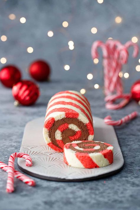 Red and white striped cake roll with one slice cut off to show a perfect spiral of chocolate peppermint whipped cream filling, with candy canes, red ornaments, and Christmas lights out of focus in the background. Peppermint Roll, Christmas Cake Roll, Candy Cane Cake, Peppermint Whipped Cream, Striped Cake, Cake Roll Recipes, Log Cake, Festive Food, Giant Candy