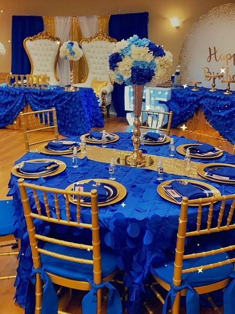 Create a delightful birthday party setup with royal blue & gold décor accents. Drape the tables with royal blue taffeta petal tablecloths layered with gold sequin runners on top for an exquisite look. Arrange white, blue, and navy blue hydrangeas in tall gold vases and place them atop round mirrors to enhance the beauty of your centerpieces tenfold. Furthermore, place gold chargers with royal blue napkins on the tables and style the chairs with cushions and sashes for a well-coordinated setup. Royal Blue And Gold Table Centerpieces, Royal Blue And Gold Decor, Royal Blue And Gold Decorations Events, Royal Blue And Gold Decorations, Royal Blue And Gold Table Setting, Blue And Gold Gala Decor, Royal Blue And Gold Centerpieces, Royal Blue And Gold Party Decorations, Royal Blue And Gold Wedding Decorations