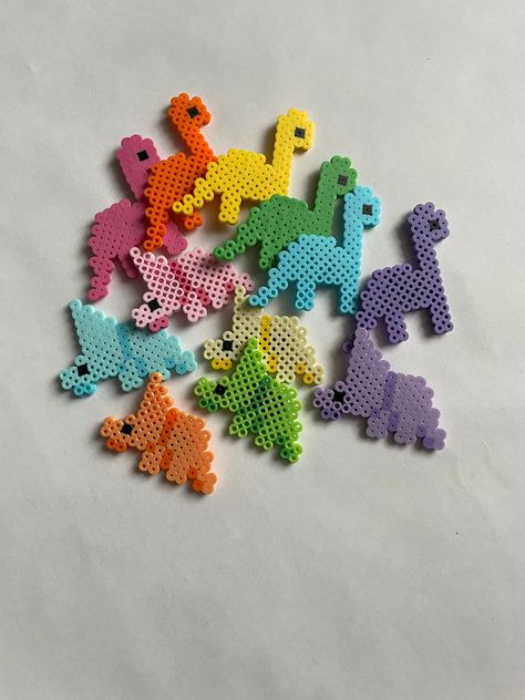 Small figures made with Perler Beads. Dinosaur  Tyrannosaurus Rex, Triceratops, and Brachiosaurus.  If you want a dinosaur or a color that isn't pictured let me know what you would like in the personalization box. If you don't want the magnet put on the back let me know in the personalization box and i'll just send the magnet unattached in case you want to add it later. Size:  Triceratops  Tyrannosaurus  Brachiosaurus  Made to order. If you have any questions please feel free to message me, I wi Succulent Perler Bead Pattern, Perler Beads Ideas Dinosaur, Dinosaur Pearl Beads, Perler Bead Orca, Ratatouille Perler Beads, Perler Bead Piggy Bank, Paw Patrol Perler Beads, Cute Melty Beads, Car Perler Bead Pattern