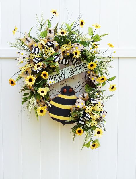 "A Large Spring Grapevine Wreath with Sunflowers and Bees done in the colors of yellow and black. A rustic wooden bee with a \"Happy Spring\" sign is surrounded by bright dancing sunflower, lots of ferns and an assortment of greenery. A designer bow in pretty patterns complement the bee theme. Approximately 34\" tall, 22\" wide and 8\" deep" Bee Wreath Ideas, Sunflowers And Bees, Spring Grapevine Wreath, Wooden Bee, Spring Wreath For Front Door, Wagon Wheels, Bee Sign, Honey Bee Decor, Summer Decorations