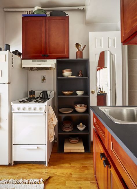 Small studio apartment kitchen corner with black storage shelf and petite stove Best Kitchen Storage, Nyc Studio Apartments, Tiny Studio Apartments, Simple Bookshelf, Furniture Apartment, Linen Bed Cover, Apartment In New York, Kitchen Addition, Nyc Studio