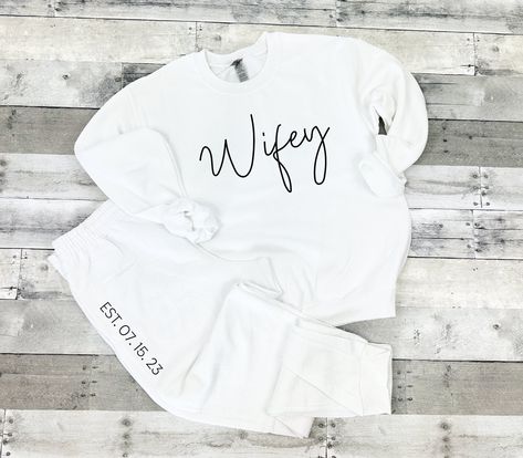 "Wifey Tracksuit, Wifey Sweatshirt, Wifey Jogger Pants, Sweatshirt and Pant Set, Honeymoon Outfit, Future Mrs Outfit, Mrs Tracksuit Matching ---------------------------------------------- Wifey Crew Neck Sweatshirt OR Wifey Jogger pants by Bride Bikini® Welcome to Bride Bikini Etsy Shop! Each listing is for ONE (1) unisex crew neck sweatshirt that will say \"Wifey\" OR a pair of jogger pants that will say \"EST. XX. XX. XX\" down the right upper leg as shown. Tees are super soft cotton or cotton Bride Jogger Set, Bridal Tracksuit, Mom And Me Shirts, Bridal Honeymoon, Wifey Sweatshirt, Mrs Sweatshirt, Honeymoon Style, Bridal Party Outfit, Honeymoon Outfits