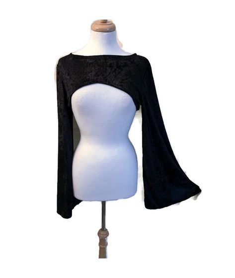 This shrug is made of stretch velvet fabric.   It has extra long flared bell sleeves. It fits above the bust in the front. It is available in black, red, or purple.  Small fits a bust of 30" to 33", medium fits a bust of 33" to 36". Small and Medium sleeves measure 17" around bicep area. Large fits a bust of 36" to 39",  XLarge fits a bust of 39" to 42" . Large and Xlarge sleeves measure 18" around bicep area. 2X fits a bust of 42" to 45", 3X fits a bust of 45" to 48".  2X and 3X sleeves measure Goth Sleeves, Velvet Bolero, Descendants Dr, Genshin Oc, Core Aesthetics, Black Shrug, Goth Baby, Dr Closet, Marvel Clothes