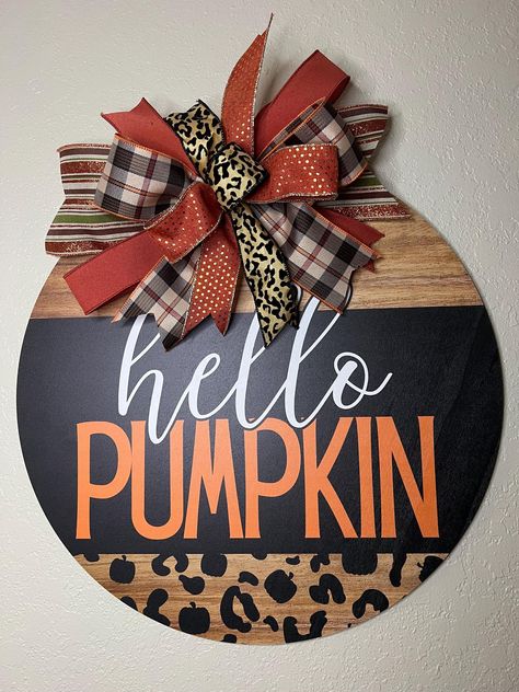 Bring a touch of fall charm to your home with this stylish "Hello Pumpkin" door hanger! This eye-catching sign combines a trendy leopard print with rustic wood accents and vibrant orange lettering, making it the perfect piece to celebrate the autumn season. Topped with a beautifully crafted plaid and leopard print bow, this door hanger adds a chic and festive flair to your front door or any indoor space. This pumpkin-shaped sign is ideal for those who love a mis of farmhouse and modern decor. Whether you're decorating for Halloween or simply embracing the fall season, this "Hello Pumpkin" sign will greet your guests with warmth and style. Made from high-quality materials, this door hanger is designed to last and can be used year after year. Perfect as a gift for friends and family or as a Rustic Farmhouse Front Door, Pumpkin Door Sign, Hello Pumpkin Sign, Cricket Designs, 2x4 Projects, Welcome Signs Front Door, Round Signs, Fall Wood Signs, Farmhouse Front Door