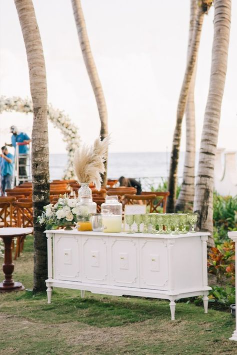 White credenza with aguas frescas, green glass. Cocktail hour. Beach wedding Belize Wedding, White Credenza, Welcome Drink, Agua Fresca, Wedding Drink, Cocktail Hour, Belize, Green Glass, Credenza