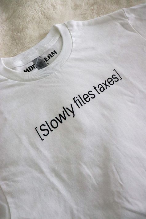 A white t-shirt from Moonbeam BLVD with black lettering that says, "Slowly files taxes". Ironic Tees, Tees Aesthetic, Ironic Tshirts, Tax Filing, Outfits Modest, Iron Shirt, Shirt Design Inspiration, Filing Taxes, Meme Tshirts