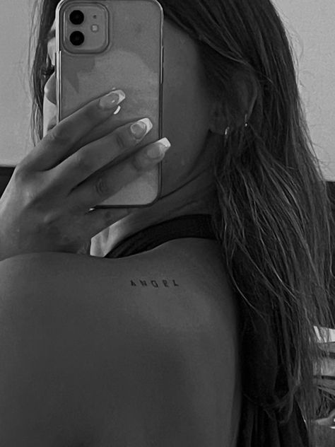 black and white shoulder tattoo Back Of Shoulder Tattoo Words, Back Shoulder Word Tattoos For Women, Daughter Of An Angel Tattoo, Writing Shoulder Tattoo, Inside Shoulder Tattoos For Women, Left Back Shoulder Tattoo Women, Angel Written Tattoo, Angel Collar Bone Tattoo, Tattoo Behind Shoulder