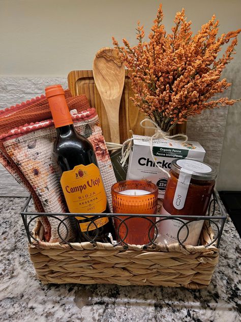 Fall themed gift basket with orange and wood accents. Gift basket is pasta date-night themed and includes red Italian wine, gluten free chickpea pasta, pasta sauce, candle, kitchen towel, wooden spoon and orange accents. Accents are decorative floral and tweed. Pasta Night Gift Basket, Wine And Pasta Gift Basket Ideas, Date Night Hamper, Pasta Making Gift Basket, Italian Basket Gift Ideas, Charcuterie Basket Ideas, House Warming Basket Diy, Diy Pasta Gift Basket, Bundled Gifts