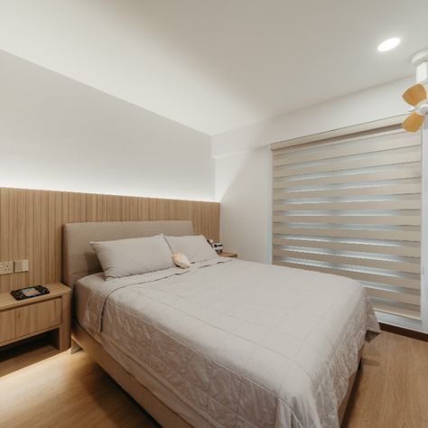 This master bedroom showcases a minimalist design with a soothing neutral palette. Wood paneling behind the headboard adds warmth, while soft lighting creates a cozy feel. A large window with blinds brings in natural light and outdoor views, promoting relaxation and tranquility. Window With Blinds, Large Window, Neutral Palette, Large Windows, Wood Paneling, Soft Lighting, Natural Light, Minimalist Design, Blinds