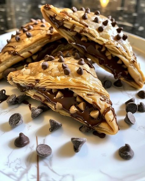 Chocolate Chip Cookie Dough Turnovers 🍫🥐 Ingredients: For the Turnovers: - 1 sheet puff pastry, thawed - 1/2 cup mini chocolate chips - 1/4 cup peanut butter chips (optional) For the Cookie Dough Filling: - 1/4 cup unsalted butter, softened - 1/4 cup brown sugar, packed - 1/4 cup granulated sugar - 1/2 tsp vanilla extract - 2 tbsp milk - 3/4 cup all-purpose flour (heat-treated for safety) For the Drizzle: - 1/2 cup semi-sweet chocolate chips, melted Directions: 1. Prepare Cookie Dough F... Cookie Dough Filling, Vegan Bakery, Puff Pastry Sheets, Delicious Snacks, Pastry Sheets, Peanut Butter Chips, Fancy Desserts, Cookies Recipes, Delicious Snacks Recipes