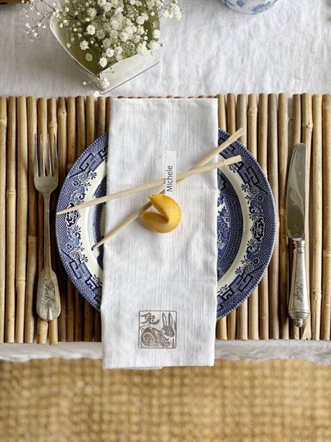 It's tablescape day for my dinner club and we're hosting an Asian inspired gathering. I'm sharing the best ideas for hosting a Chinese themed dinner party. My great grandmothers blue transferware with an Asian pattern was the inspiration for my Chinese themed table decor. Bamboo placemats, chopsticks, fortune cookies and Chinese takeout containers were other elements I incorporated. An Asian pattern teapot and the take-out containers made great vases for flowers for the centerpiece. Asian Table Setting Dinner Parties, Chinese Takeout Party, Hibachi Party Table Setting, Japanese Inspired Tablescape, Chinese Table Setting Ideas, Asian Dinner Table Setting, Asian Inspired Tablescape, Chinese Food Dinner Party, Chinese Dinner Party Decorations