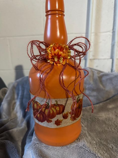 This a 1/2 gallon Buffalo Trace bottle.  Painted in a rustic orange with a beautiful pumpkin ribbon around the center.  Accented with a red twine bow an autumn flower. Painted Whiskey Bottles, Recycled Wine Bottle Art, Whiskey Bottle Crafts, Fall Mason Jar Crafts, Halloween Wine Bottles, Wine Bottle Crafts Christmas, Fall Pumpkin Centerpieces, Art Rooms, Autumn Diy